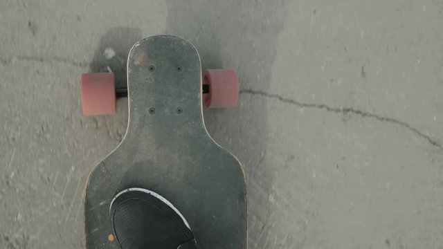 Man riding a longboard, a plan view on the move, close-up, first-person view. Pov view on skateboard and legs