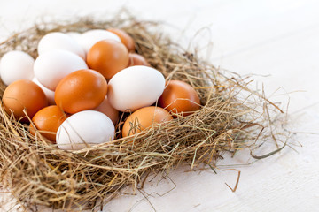 Fresh country eggs with straw on rustic wooden white table