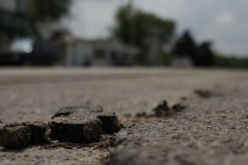 Detail von aufgebrochenem Asphalt auf Straße im Sommer