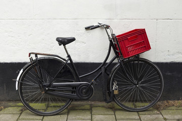 Fototapeta na wymiar Black bicycle with red basket at white wall