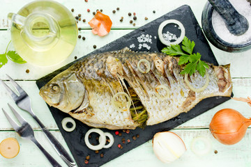 Whole fried fish on kitchen table with ingredients