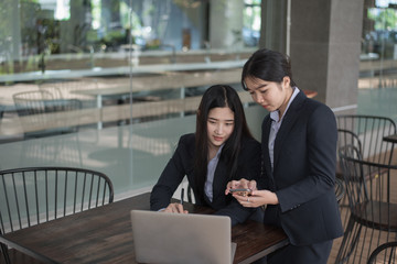 Two business woman young asian girls sitting at the laptop while discussing business matters