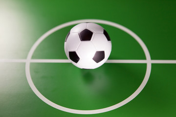 Toy soccer ball in a midfield, in the center of the green field..