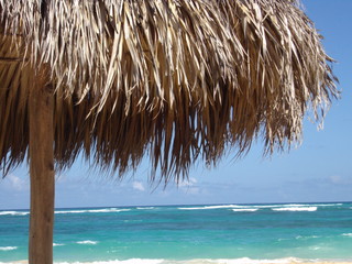 Fototapeta na wymiar Mer turquoise depuis plage sable fin sous parasol en paille 