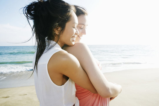 Side view of smiling couple hugging on beach