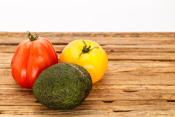 A pair of tomatoes and an avocado grouping with white background