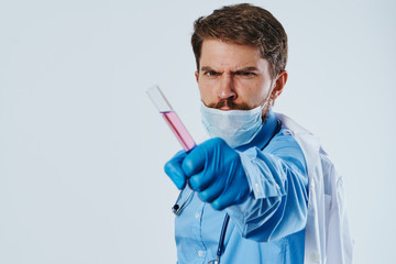 A man with a beard on a light background holds laboratory utensils in a medical dressing gown, doctor, science
