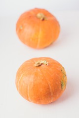 Two mini pumpkins on white background. Studio shot of orange pumpkins on wooden table. Copy space for the text