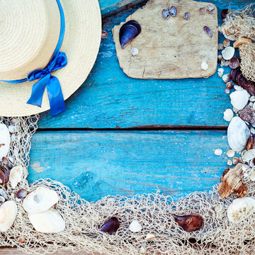 Summer vacation relaxation background theme with seashells, fishing net, hat, rope, stones and weathered wood blue background with copy space. Vintage toning, square format