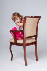 девочка выглядывает из-за спинки кресла, портрет. девочка сидит в кресле
