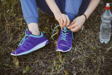 Sport concept,blue sneakers for running  with walkgirlslying on grass. Girl sitting on pitch, no face, legs in professional sport shoes, closeup. Outdoors, sunlight, field