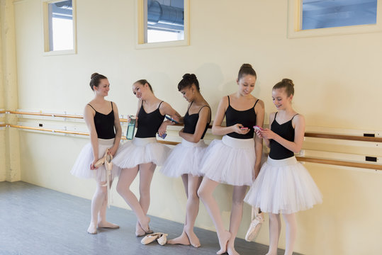 Girls talking and texting on cell phones in ballet studio
