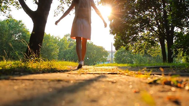  Girl walking in the green park enjoying the golden sunset