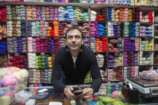 Mixed Race Man Texting On Cell Phone At Yarn Store