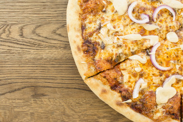 Hot pizza with melting cheese on a rustic wooden table. Delicious meal in the restaurant.