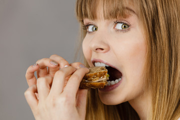 Woman eating sandwich, taking bite