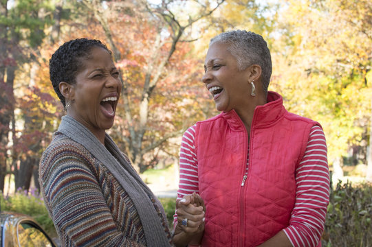 African American women holding hands and laughing outdoors
