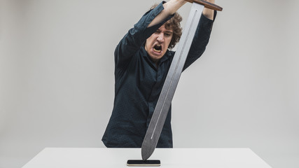angry man hitting his phone with a sword