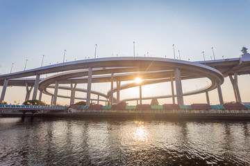 Fototapeta na wymiar Modern concrete bridges the ways across big river in sunset time with sunlight.