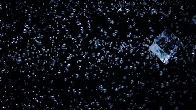 The ice falls into the water, Background,  Water bubbles in slow motion