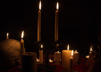 Burning candles and human skull in dark room. Halloween witchraft concept. 