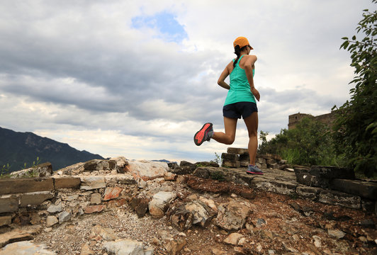 young woman trail runner running on great wall in the top of mountain