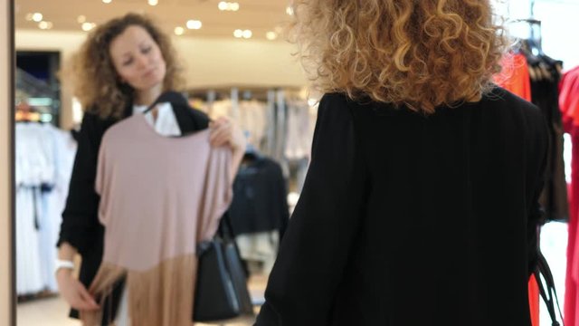 Woman Shopping For Clothes Looking In Mirror In Clothing Store. 4K. 