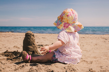 Little girl with sand castle enjoying the beach