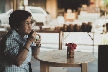 Old Asian Woman with a glasses eat icecream in Vintage Tone