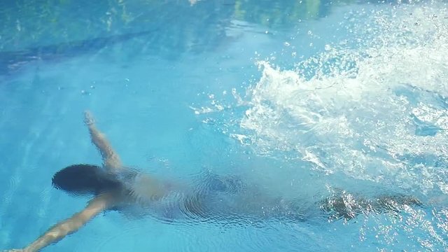 Brunette slim woman jums in water and swimming underwater in the pool in slow motion. 1920x1080