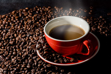 Hot coffee in red cup and coffee beans are the background.