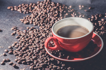 Hot coffee in red cup and coffee beans are the background.