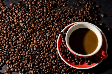 Hot coffee in red cup and coffee beans are the background.