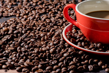 Hot coffee in red cup and coffee beans are the background.
