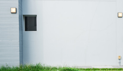 Grey concrete wall with lamp and have green grass at the bottom