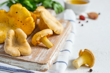 Raw chanterelle mushrooms on a cutting board closeup on white background