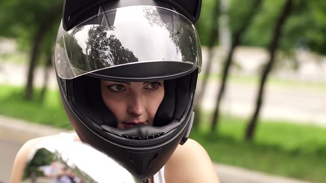 Portrait of young sexy girl in the black helmet on a motorcycle.