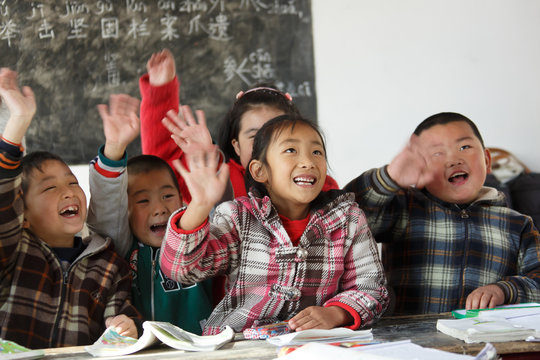 Primary school student raising hands together in the classroom
