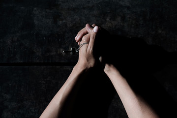 Hands praying with cross in a wooden table