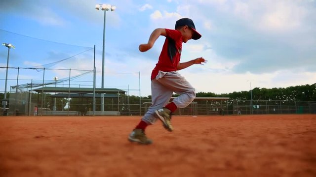 Slow Motion of little kid running to first base and sliding at baseball field