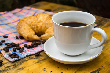 Cups of coffee and croissants On an old wooden floor, leaf background