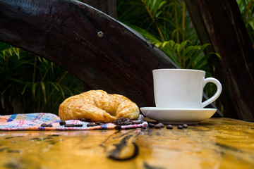 Cups of coffee and croissants On an old wooden floor, leaf background
