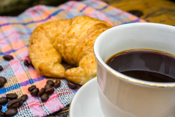 Cups of coffee and croissants On an old wooden floor, leaf background