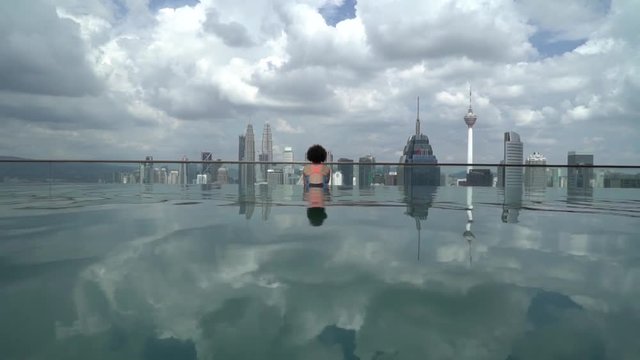 Woman watching the city in a skyline swimmingpool