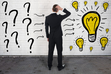 Confused Businessman Looking At Question Marks And Light Bulbs