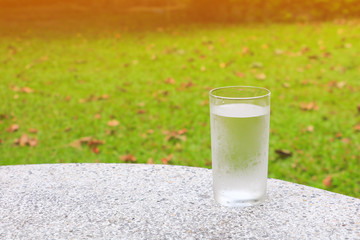 glass of water ice on terrazzo floor table with nature background and copy space add text