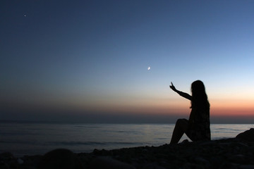 Profile silhouette of a woman looking on the beach at sunset
