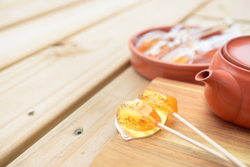 Candy lollipop and teapot on wooden background