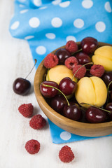 Ripe berries in a plate on a wooden table.
