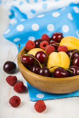 Ripe berries in a plate on a wooden table.